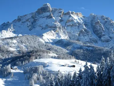 a mountain covered in snow with trees and a lake at Larjëi in San Cassiano