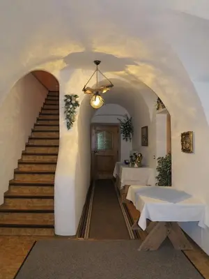 a hallway with a staircase with two tables and a chandelier at Larjëi in San Cassiano