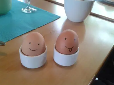 two eggs with faces painted on them sitting on a table at Pension Sonnalp in Ortisei