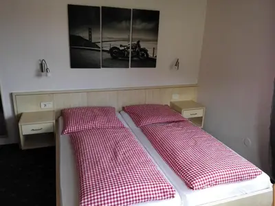 two beds with red and white checked pillows in a room at Pension Sonnalp in Ortisei