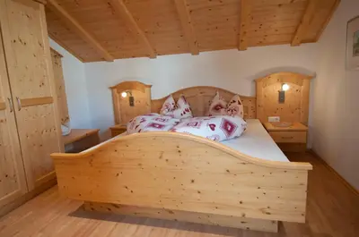 a bedroom with a large wooden bed with four pillows at Platterhof in Avelengo