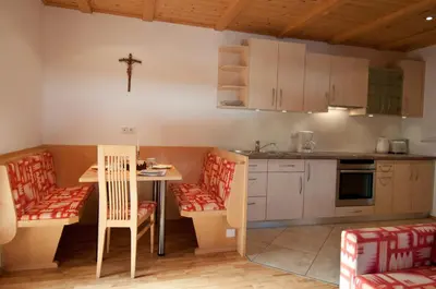 a kitchen with a table and chairs and a cross on the wall at Platterhof in Avelengo