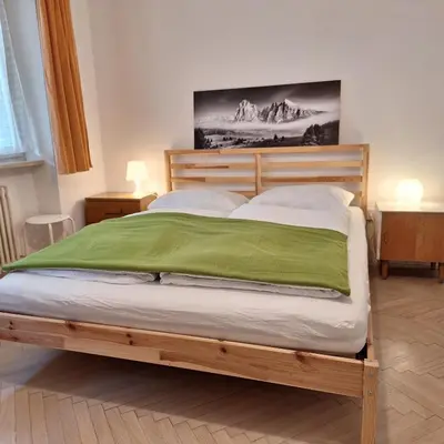 a bedroom with a wooden bed with a green blanket at apartment center pepi in Ortisei