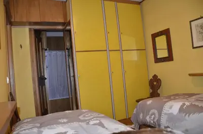 a bedroom with two beds and a yellow wall at Ground floor with garden in San Vito di Cadore