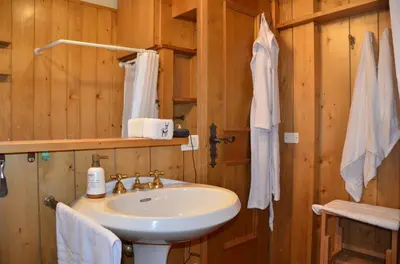 a bathroom with a white sink in a wooden room at Ground floor with garden in San Vito di Cadore