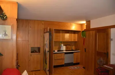a kitchen with wooden walls and wooden cabinets and a refrigerator at Ground floor with garden in San Vito di Cadore