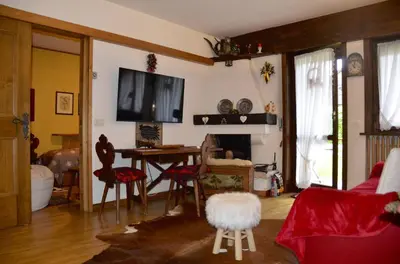 a living room with a table and a tv on the wall at Ground floor with garden in San Vito di Cadore