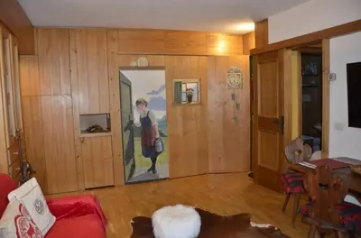 a living room with a painting of a woman on the wall at Ground floor with garden in San Vito di Cadore