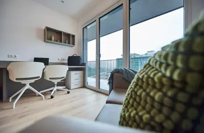 a living room with a desk and chairs and a balcony at Ferrari Tower in Bolzano