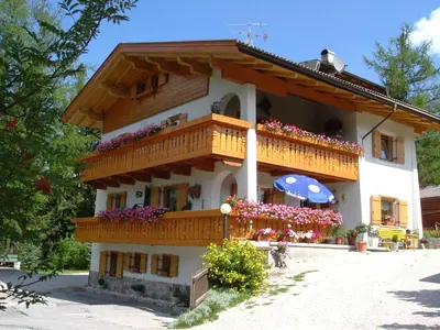 a building with a balcony with flowers and an umbrella at Elmes in La Villa