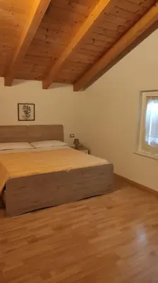 a bedroom with a bed and a wooden floor at Appartamento vacanza Coredo Trentino in Coredo