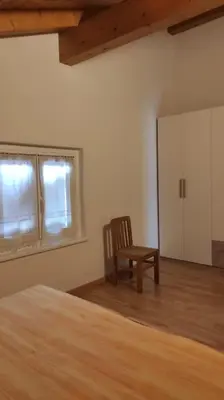 a bedroom with a bed and a chair and a window at Appartamento vacanza Coredo Trentino in Coredo