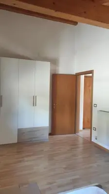 an empty room with white cabinets and a wooden floor at Appartamento vacanza Coredo Trentino in Coredo