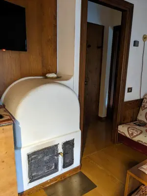 a living room with a white stove in a room at Appartamento Duplex San Vito di Cadore in San Vito di Cadore