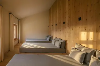 a bedroom with two beds and a wooden wall at Zallinger Dolomites in Seiser Alm