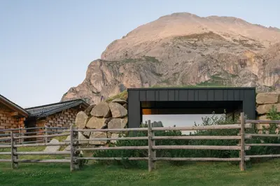 a building with a fence and a mountain in the background at Zallinger Dolomites in Seiser Alm