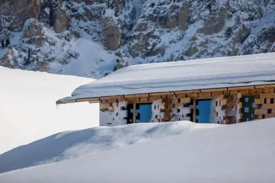 a building covered in snow in front of a mountain at Zallinger Dolomites in Seiser Alm