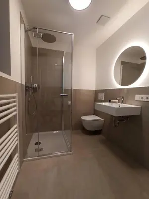 a bathroom with a shower and a toilet and a sink at Nido City Studio in Brixen