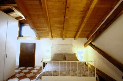 a bed in a room with a wooden ceiling at NIDO SUL CERMIS Affittacamere in Varena