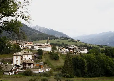 a village on a hill with mountains in the background at NIDO SUL CERMIS Affittacamere in Varena