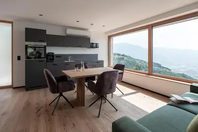 a kitchen and living room with a table and chairs at Noelani natürliches Waldidyll in San Genesio Atesino