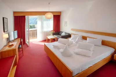 a bedroom with a large bed and a living room at Hotel Weingarten in Naturno
