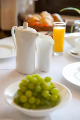 a plate of green grapes on a table with orange juice at Hotel Weingarten in Naturno