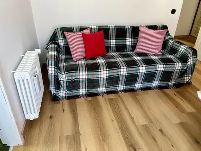 a plaid couch with two red pillows in a living room at Casa ai Dossi in Bellamonte