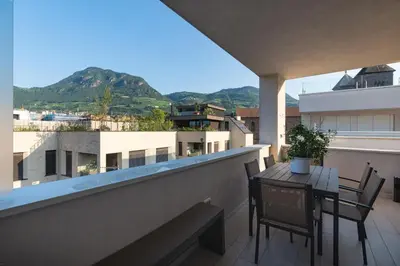 a balcony with a table and chairs on a building at SWEETHOME TALVERA - con Garage in Bolzano