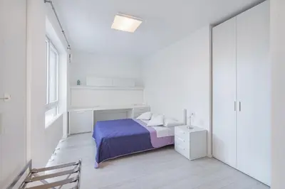 a white bedroom with a bed and a window at SWEETHOME TALVERA - con Garage in Bolzano