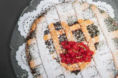 a cake with fruit on top of it on a plate at Hotel Daniel in Selva di Val Gardena