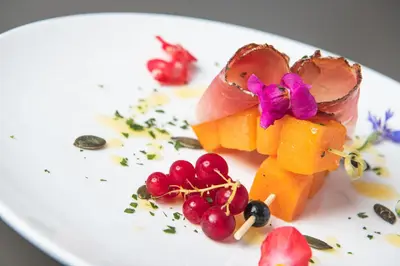 a plate of food with fruit and flowers on it at Hotel Daniel in Selva di Val Gardena