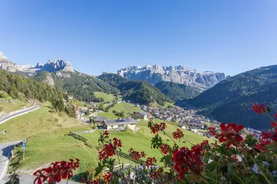 a bedroom with a bed and a table and a desk at Hotel Daniel in Selva di Val Gardena