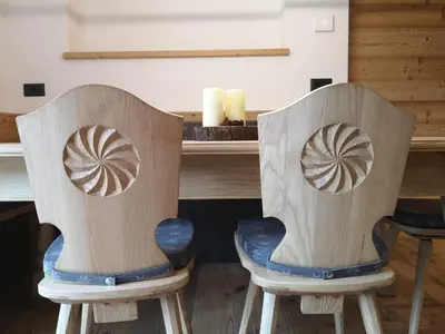 two wooden chairs with carved designs on their backs at Càbassa Moena in Moena