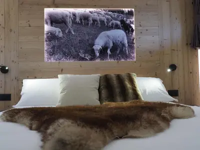 a cat laying on a bed with a herd of sheep at Càbassa Moena in Moena