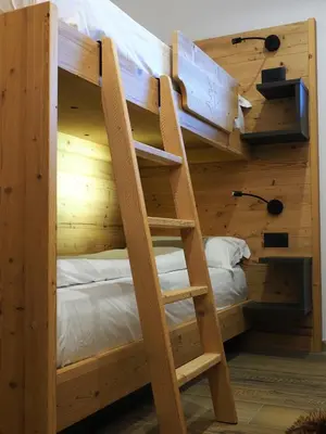 a bunk bed with a ladder in a room at Càbassa Moena in Moena