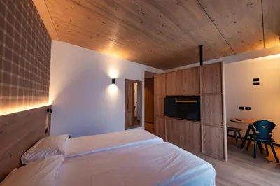 a bedroom with a bed and a tv and a table at mySHH in Vigo di Fassa