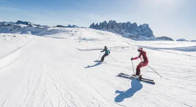 two people are skiing down a snow covered slope at Dolomiti Sot i piz in Piaia