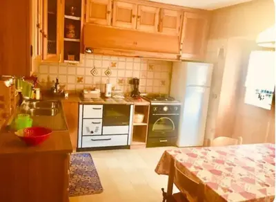 a kitchen with a refrigerator and a table in it at Dolomiti Sot i piz in Piaia