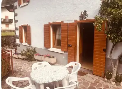 a patio with a table and chairs and a building at Dolomiti Sot i piz in Piaia