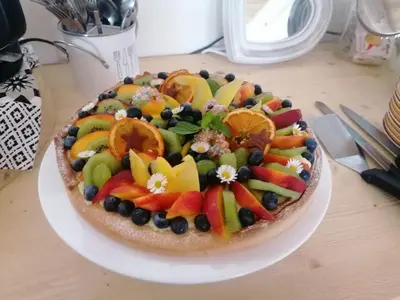 a cake with fruit on a plate on a table at B&B Sass de Mura in Fiera di Primiero