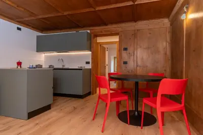 a kitchen and dining room with a table and red chairs at Casa Molino La Stua - El Fornel in Falcade