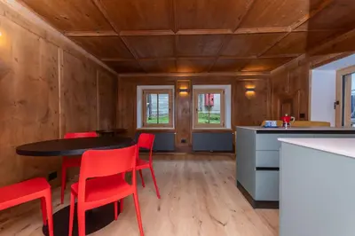 a kitchen with a black table and red chairs at Casa Molino La Stua - El Fornel in Falcade