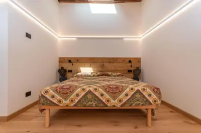 a bedroom with a bed in a room with white walls at Casa Molino La Stua - El Fornel in Falcade