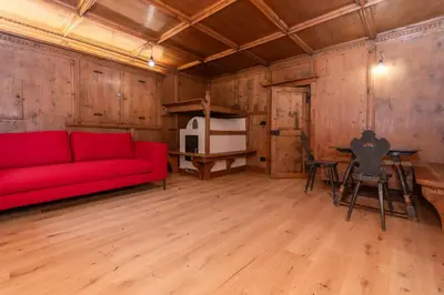 a living room with a red couch and a table at Casa Molino La Stua - El Fornel in Falcade