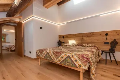 a bedroom with a large bed and a wooden wall at Casa Molino La Stua - El Fornel in Falcade