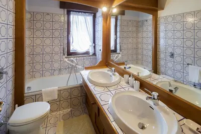 a bathroom with two sinks and a toilet and a tub at Villa Pocol - Stayincortina in Cortina dʼAmpezzo