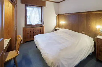 a bedroom with a large white bed and a window at Villa Pocol - Stayincortina in Cortina dʼAmpezzo