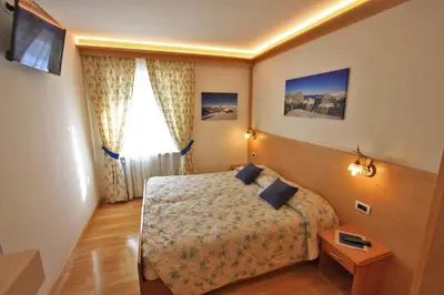a hotel room with a bed and a table at Cesa Bernard - Aloch in Pozza di Fassa