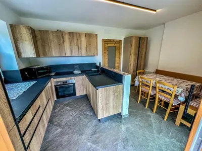 a kitchen with wooden cabinets and a table with chairs at Cesa Bernard - Aloch in Pozza di Fassa